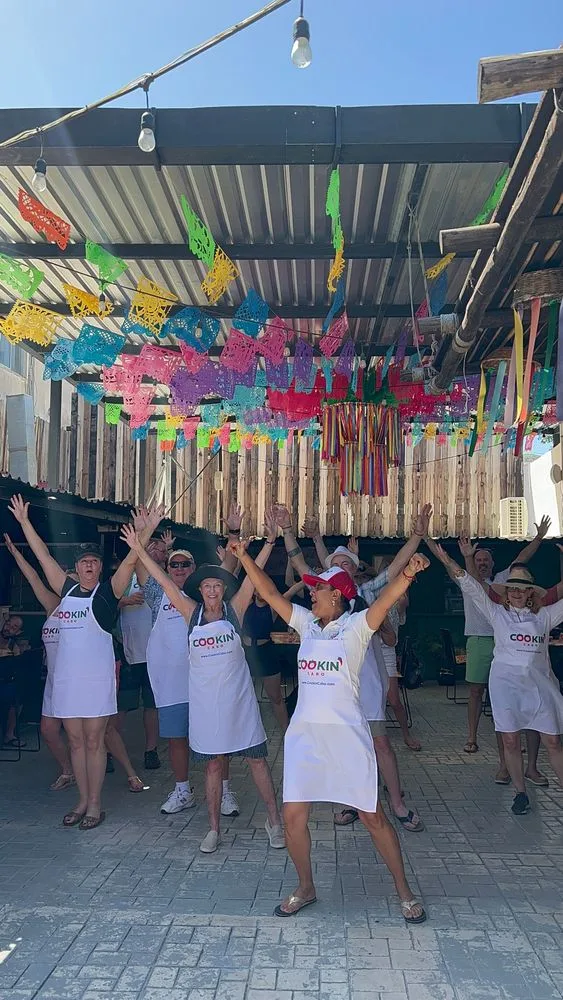 A group in cooking aprons enjoying a private Cabo culinary celebration