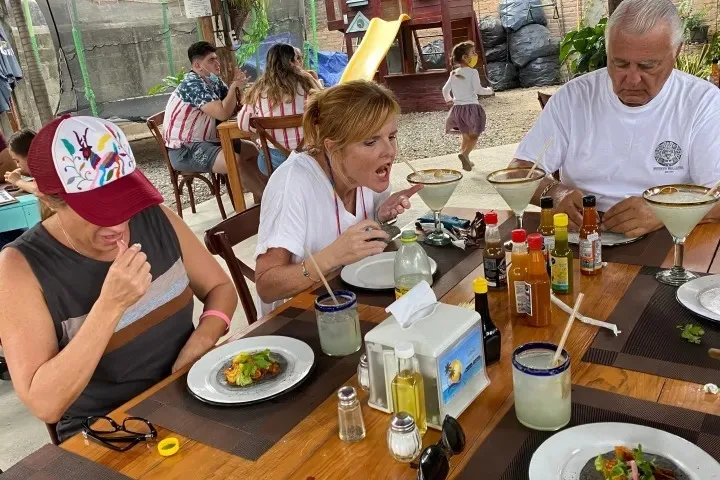 Travelers sharing food at an outdoor table during a culinary outing