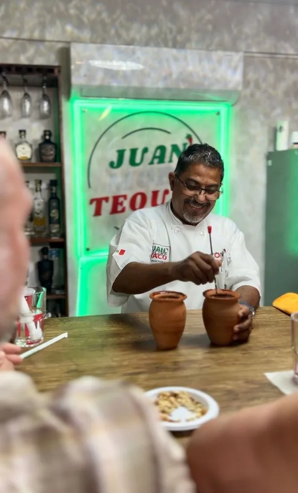 A Juan More Taco instructor preparing drinks in clay cups at a San José del Cabo tasting counter